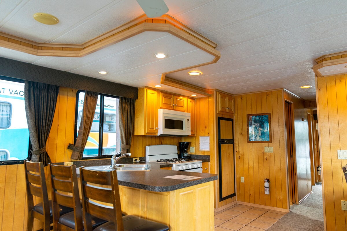 Great River Harbor_Fun n the Sun Houseboats-19 Cozy kitchen with wooden cabinets and modern appliances in a rustic vacation rental.