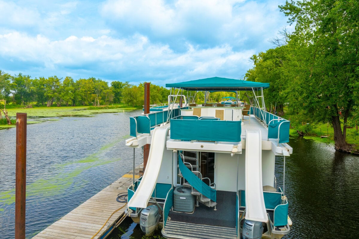 Great River Harbor_Fun n the Sun Houseboats-22 Boat tied to a dock on a river surrounded by lush green trees in Buffalo County Wisconsin.